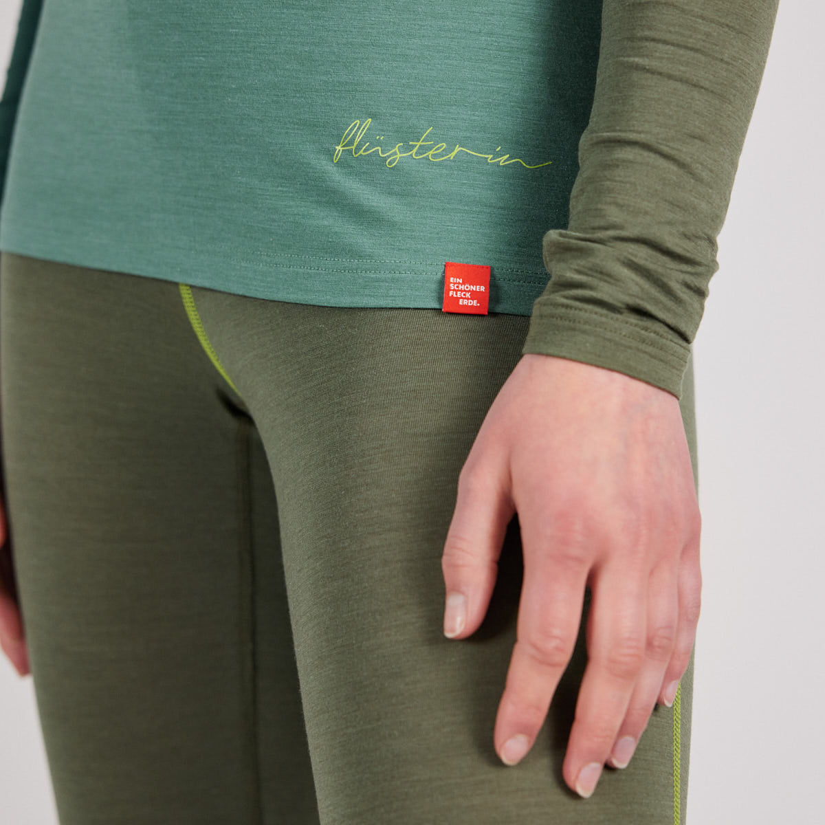 Damenunterwäsche-Set von Ein schöner Fleck Erde in Grüntönen, Langarmshirt ‚flüsterin‘ und Leggings, Detailaufnahme der Hüfte und Hand, Studioaufnahme vor neutralem Hintergrund