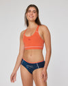 Frau in orangefarbenem Sport-Bustier und dunkelblauer Hipster Unterhose mit Aufdruck ‚Liebeseck