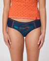 Frau in orangefarbenem Top und dunkelblauer Hipster Unterhose mit Aufdruck ‚Wilde Frau