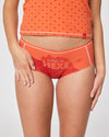 Detailansicht der rotorangenen Panty mit der Aufschrift „Schlafende Hexe“ und Landschaftsmotiv