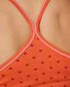Detailaufnahme des Rückens mit orangem Trägertop im Punktmuster und überkreuzten Trägern.