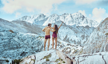 Paar in bordeauxfarbener Unterwäsche von Ein schöner Fleck Erde auf einem Felsen mit Alpenpanorama – nachhaltige Damen- und Herrenunterwäsche mit Bergmotiv inspiriert von der Natur.