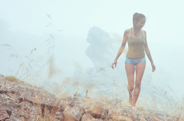 Frau wandert in der Natur im Nebel, trägt Unterwäsche von Ein schöner Fleck Erde – blaues Höschen und grünes Top mit alpinem Design, inspiriert von den Bergen.
