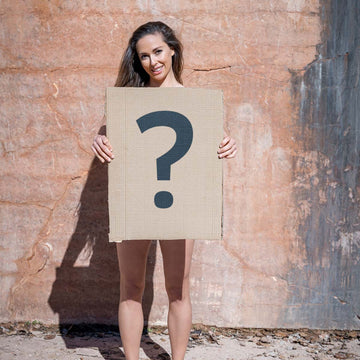 Überraschungsbox Damen – Frau hält Kartonschild mit Fragezeichen, Produktüberraschung von Ein schöner Fleck Erde