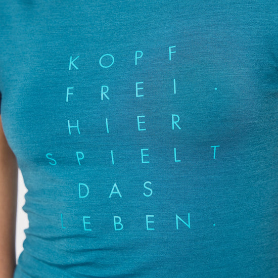 Nahaufnahme eines blauen T-Shirts mit türkisfarbenem Aufdruck ‚Kopf frei – hier spielt das Leben‘.
