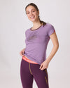 Frau trägt lilafarbenes T-Shirt mit Aufdruck Wald knallt und violette Funktionsleggings mit gelben Nähten von Ein schöner Fleck Erde, Studioaufnahme