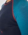 Nahaufnahme eines dunkelblauen Longsleeves mit türkisfarbenem Ärmel und roten Kontrastnähten an Schulter und Achsel.