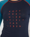Nahaufnahme eines dunkelblauen Longsleeves mit türkisfarbenen Ärmeln und rotem Aufdruck auf der Brust: ‚KOPF FREI. HIER SPIELT DAS LEBEN.‘