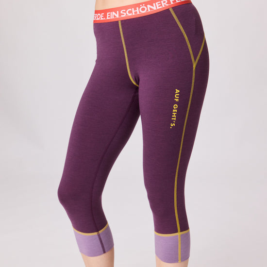 Violette 3/4-Funktionshose von Ein schöner Fleck Erde mit gelben Nähten, lilafarbenen Bündchen und rotem Bund mit Schriftzug ‚EIN SCHÖNER FLECK ERDE‘