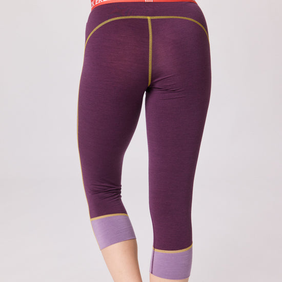 Rückansicht einer violetten 3/4-Funktionshose von Ein schöner Fleck Erde mit lilafarbenen Bündchen, gelben Nähten und rotem Bund mit Schriftzug