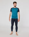 Mann trägt dunkelblaue Funktionsleggings und türkisfarbenes Kurzarmshirt von Ein schöner Fleck Erde, stehend vor neutralem Hintergrund
