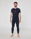 Mann trägt dunkelblaues Kurzarmshirt mit Aufdruck ‚D’ Sunnseitn‘ und passende dunkelblaue Funktionsleggings von Ein schöner Fleck Erde, stehend vor neutralem Hintergrund.