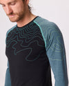 Detailaufnahme eines dunkelblauen Funktionsshirts mit hellblauen Ärmeln und Linienmuster von Ein schöner Fleck Erde, getragen von einem Mann im Studio