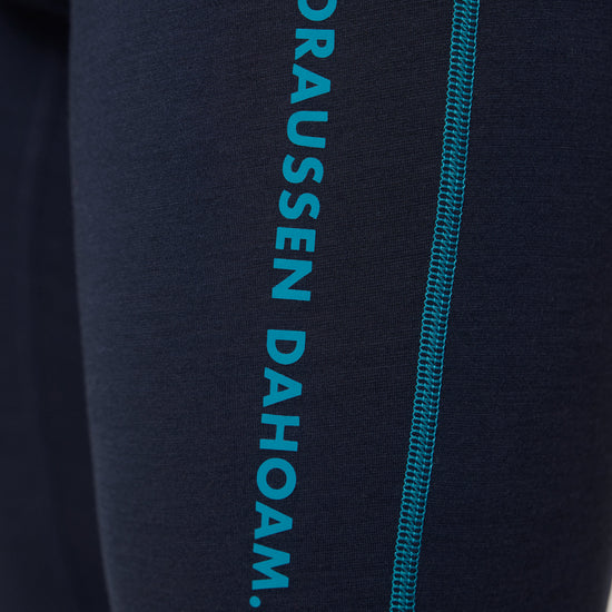 Detailaufnahme einer dunkelblauen Funktionsleggings mit türkisfarbener Naht und seitlichem Aufdruck ‚DRAUSSEN DAHOAM‘ von Ein schöner Fleck Erde.